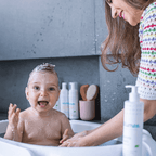 Mãe sorridente lavando o cabelo do bebê com Sabonete Líquido Blumee no banho