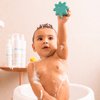 Bebê sorrindo com espuma na cabeça segurando brinquedo, banho com Blumee