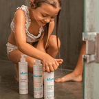 Criança usando produtos do Kit Trio Blumee durante o banho no chuveiro